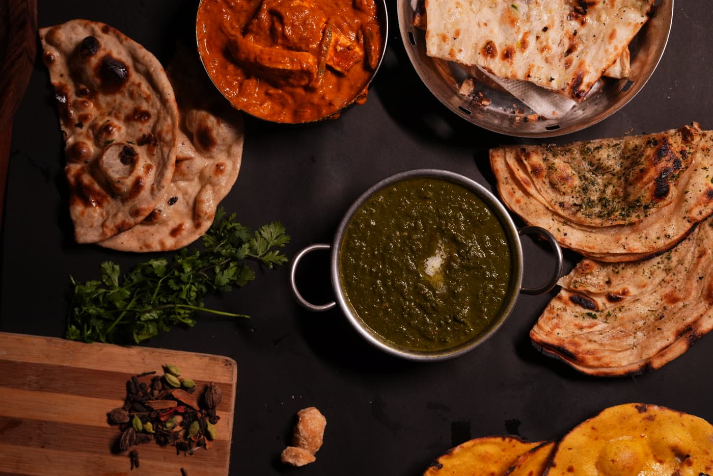 A spread of saag, butter chicken and tandoor breads